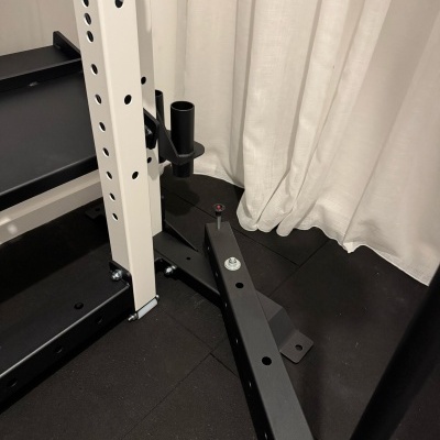 Estrutura metálica preta e branca robusta de equipamento de ginásio com perfurações circulares