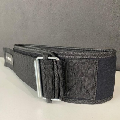 Cinto largo preto com fecho metálico sobre superfície branca