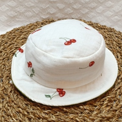 Chapéu branco com cerejas vermelhas sobre base trançada castanha