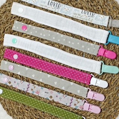 Sete fitas para prender chupetas com padrões variados em fundo de tapete de ráfia