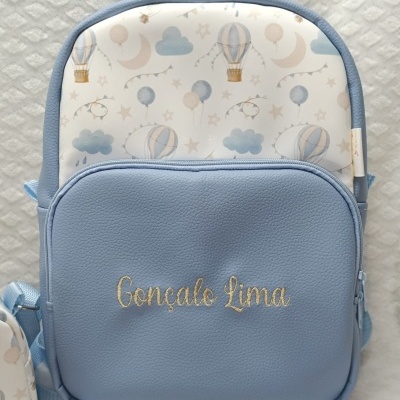Mochila azul clara com padrão de balões e nome bordado