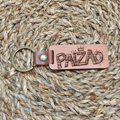 Porta-chaves de madeira com palavra PAIZÃO gravada e argola metálica sobre fibra natural trançada.