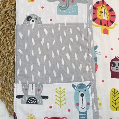 Toalha ou fralda de tecido com estampado infantil colorido de animais e detalhe cinzento com manchas brancas