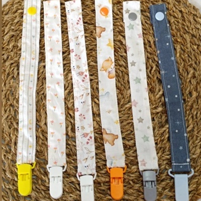 Seis fitas com prendedores coloridos e estampas variadas sobre base de palha trançada