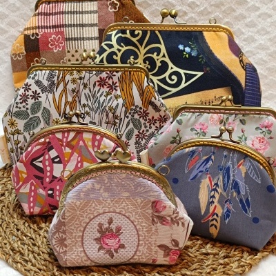 Seis carteiras de tecido com padrões e armações metálicas douradas sobre base trançada.