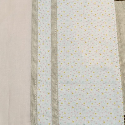 Capa ou organizer tecido com padrão de pontos coloridos e faixas bege, em superfície natural