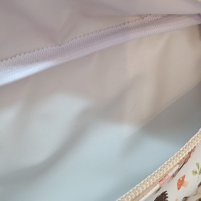 Interior de bolsa branca com zipper e padrão de animais no exterior