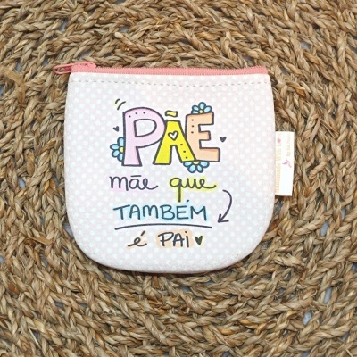 Bolsa pequena rosa com fecho de correr e texto colorido, sobre tapete de fibras naturais