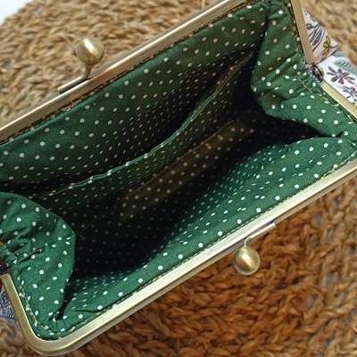 Carteira com interior verde com bolinhas brancas e moldura metálica dourada