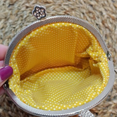 Bolsa pequena com fecho metálico e interior amarelo às bolinhas brancas
