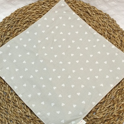 Pano quadrado cinza com corações brancos em base de palha trançada
