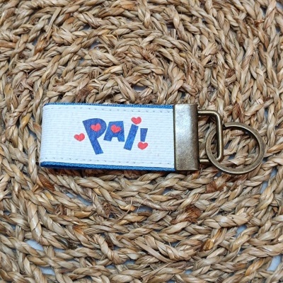 Chaveiro azul e branco com texto PAI! e corações vermelhos