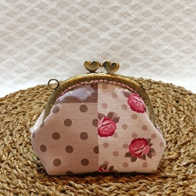Bolsa pequena em tecido com padrão de bolinhas e flores e fecho metálico com corações