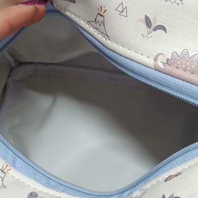 Bolsa com fecho azul claro e padrão de dinossauros e vulcões