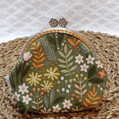 Carteira pequena estampada com flores em tecido verde com fecho metálico prateado.