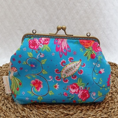 Mala azul de tecido com padrão floral e fecho metálico dourado