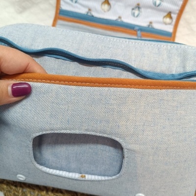 Bolsa ou estojo azul claro com aba alaranjada e interior estampado