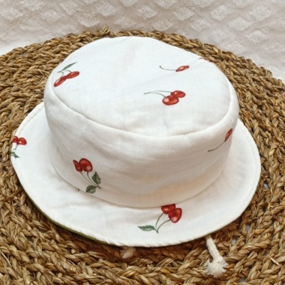 Chapéu branco com padrão de cerejas em tapete trançado de fibra natural