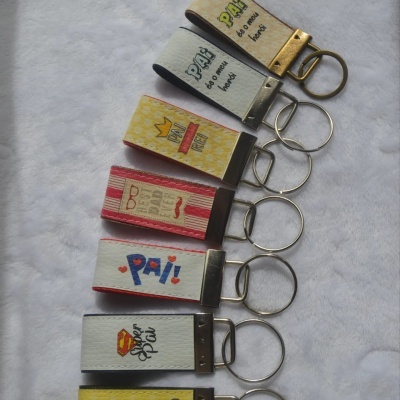 Sete porta-chaves de tecido com textos relacionados a pai sobre fundo branco macio