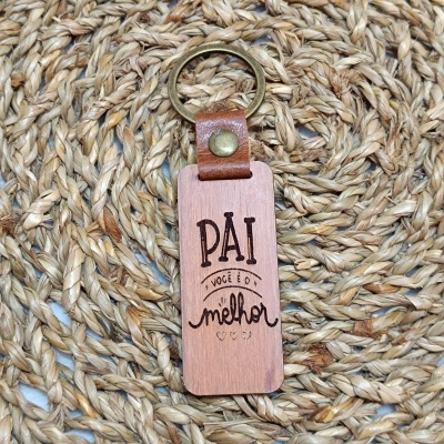 Chaveiro de madeira com frase para pai sobre tapete de fibras trançadas.