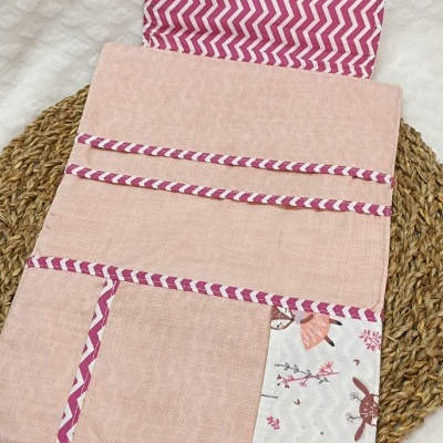 Organizador de tecido rosa com bolsos e padrão ziguezague branco e rosa.