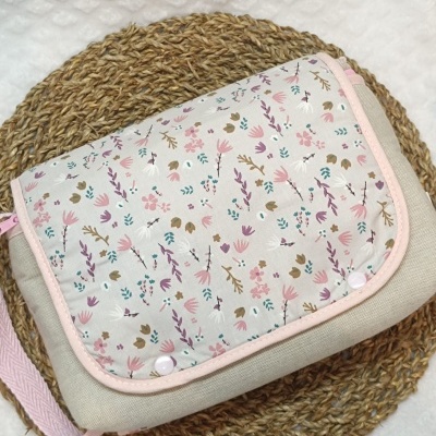 Bolsa de tecido bege com padrão floral colorido sobre base trançada redonda