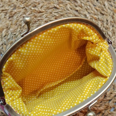 Interior da carteira amarela com bolinhas brancas e fecho metálico