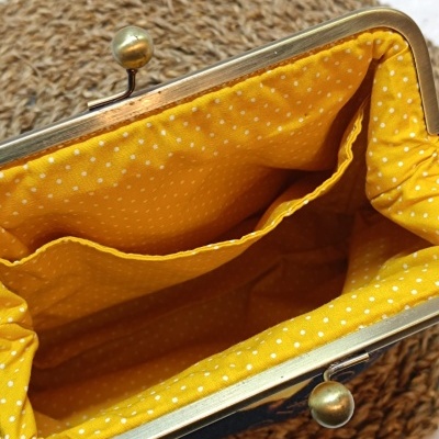 Interior de mala amarela com pontos brancos e fecho metálico dourado