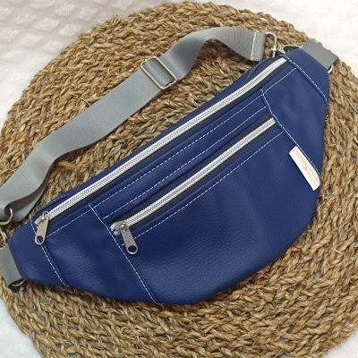 Bolsa tipo pochete azul com alça cinza sobre esteira redonda