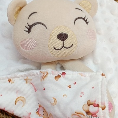 Peluche ursinho bege com tecido estampado branco com coelhos e estrelas.