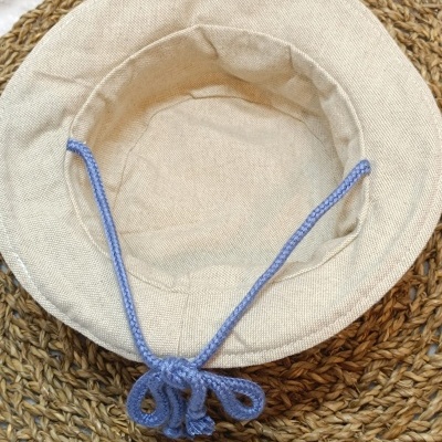 Chapéu bege claro com cordão azul sobre suporte trançado castanho