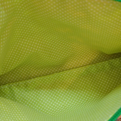 Interior de bolsa verde com padrão de pontos brancos e borda verde escura