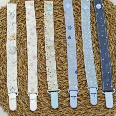 Seis fitas para chuchas coloridas com padrões e clips sobre superfície de corda.