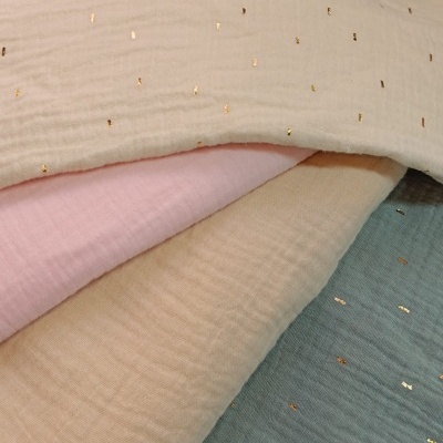 Tecidos macios em creme, rosa e azul com pontos dourados