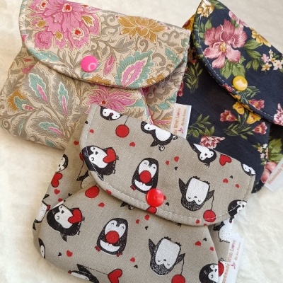 Três bolsas de tecido com padrões florais e pinguins sobre fundo branco