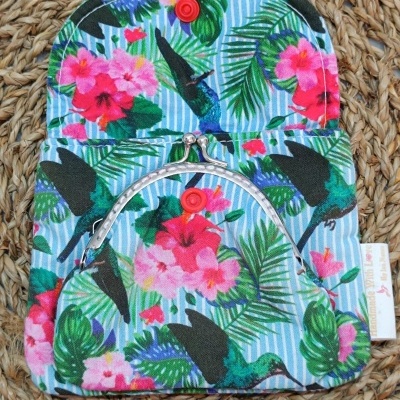 Carteira de tecido colorido com padrão de flores e pássaros com botão e fecho metálico.