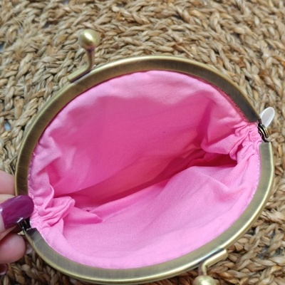 Carteira metálica dourada com interior rosa em tecido e superfície trançada