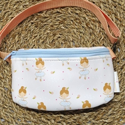 Pochete com padrão de bailarinas, fecho azul e alça laranja num tapete de rattan