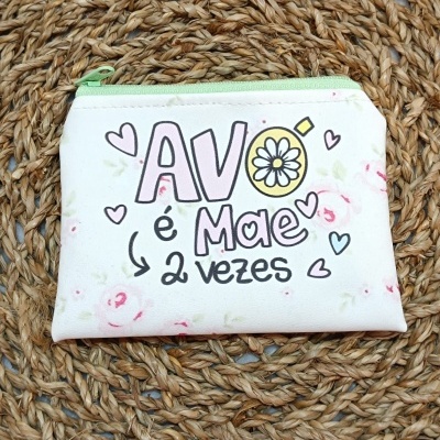 Bolsa pequena branca com padrão floral e texto sobre superfície de palha