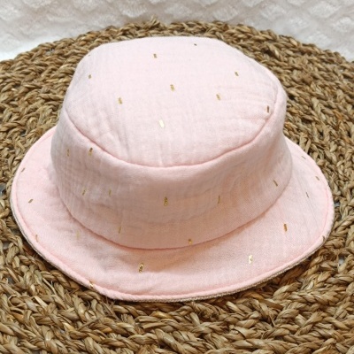 chapéu pescador rosa claro com pontos dourados sobre base de fibras trançadas