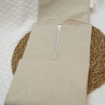 Mala de tecido bege claro aberta sobre base de palha trançada