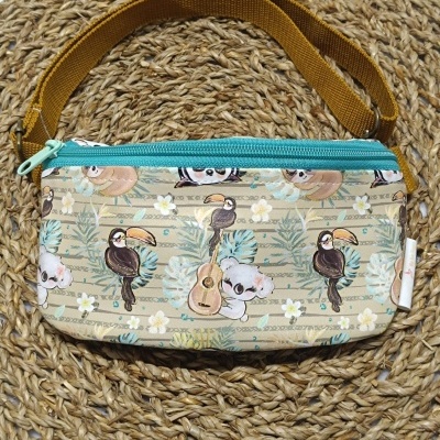 Pochete com estampa de animais e flores com fecho azul e correia amarela sobre tapete de fibra