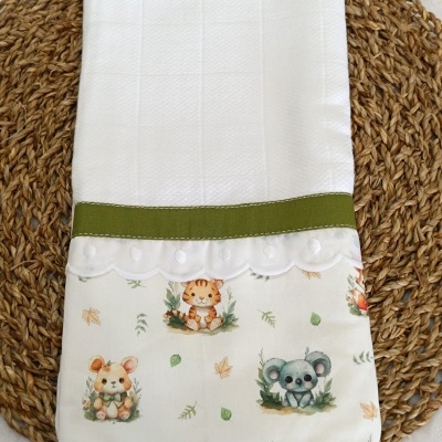 Toalha branca acolchoada com faixa verde e parte inferior com estampas de animais em fundo creme