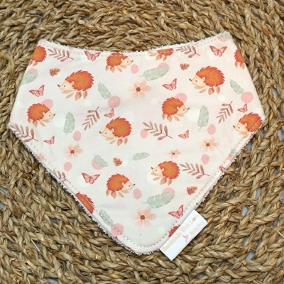 Bandana para bebé com padrão de ursos, flores e folhas sobre tapete trançado