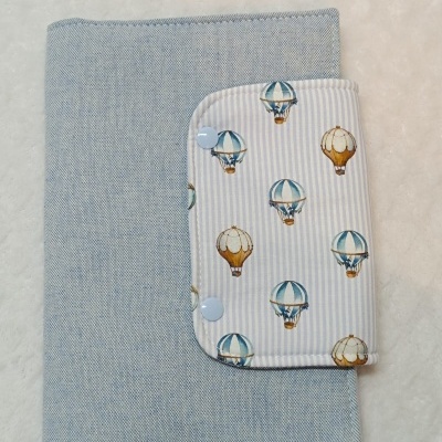 Capa de tecido azul com aba estampada de balões de ar quente e botões azuis