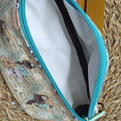 Bolsa pequena com padrão de tucanos e ursos, zíper azul turquesa, interior branco