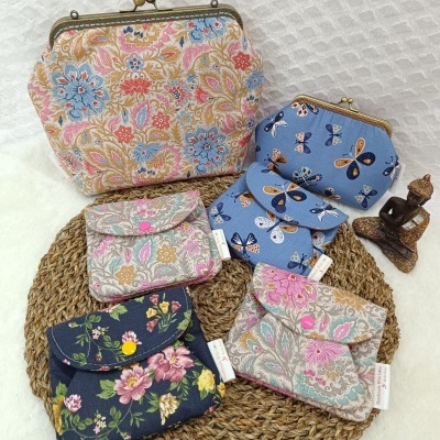 Carteiras e bolsas de tecido com padrões florais e borboletas em base trançada