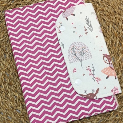 Capa de tecido rosa com padrão zigzag e aba branca com estampado de animais e plantas