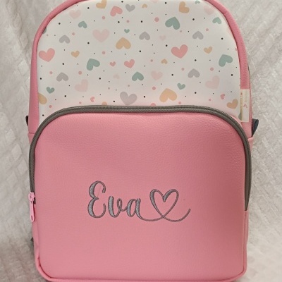 Mochila rosa com bolso frontal bordado Eva e padrão de corações coloridos.