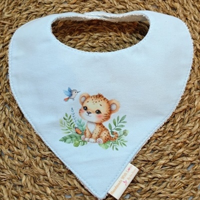 Babete branco com desenho de filhote de leopardo e beija-flor sobre tapete de fibra trançada